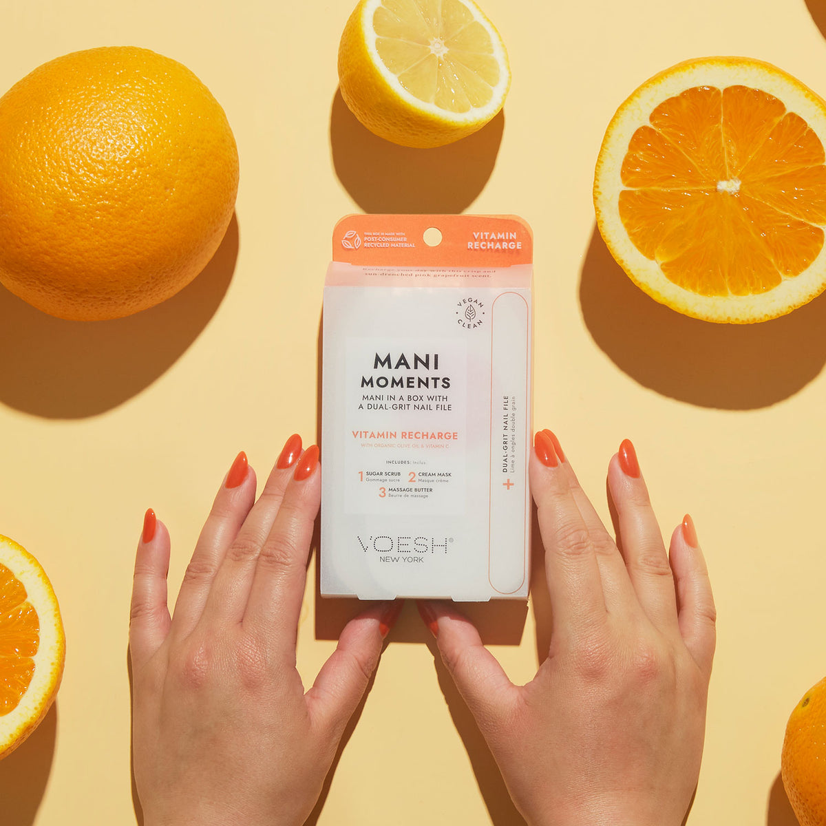 Manicured hands on a yellow background holding VOESH's Mani Moments product.