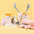 Scalp Massager, Pedi Moments Mango Delight, Crystal Clear Head-To-Toe Cleansing Soap on top of Natural Loofah Soap Dish, Hair Towel & Scrunchie Set, Clear Beach Bag with Mani Moments Vitamin Recharge, Sugar Scrub + Bubble Wash Citrus Crush, and Vitamin C Shower Filter Citrus Crush inside, pictured on a yellow background.