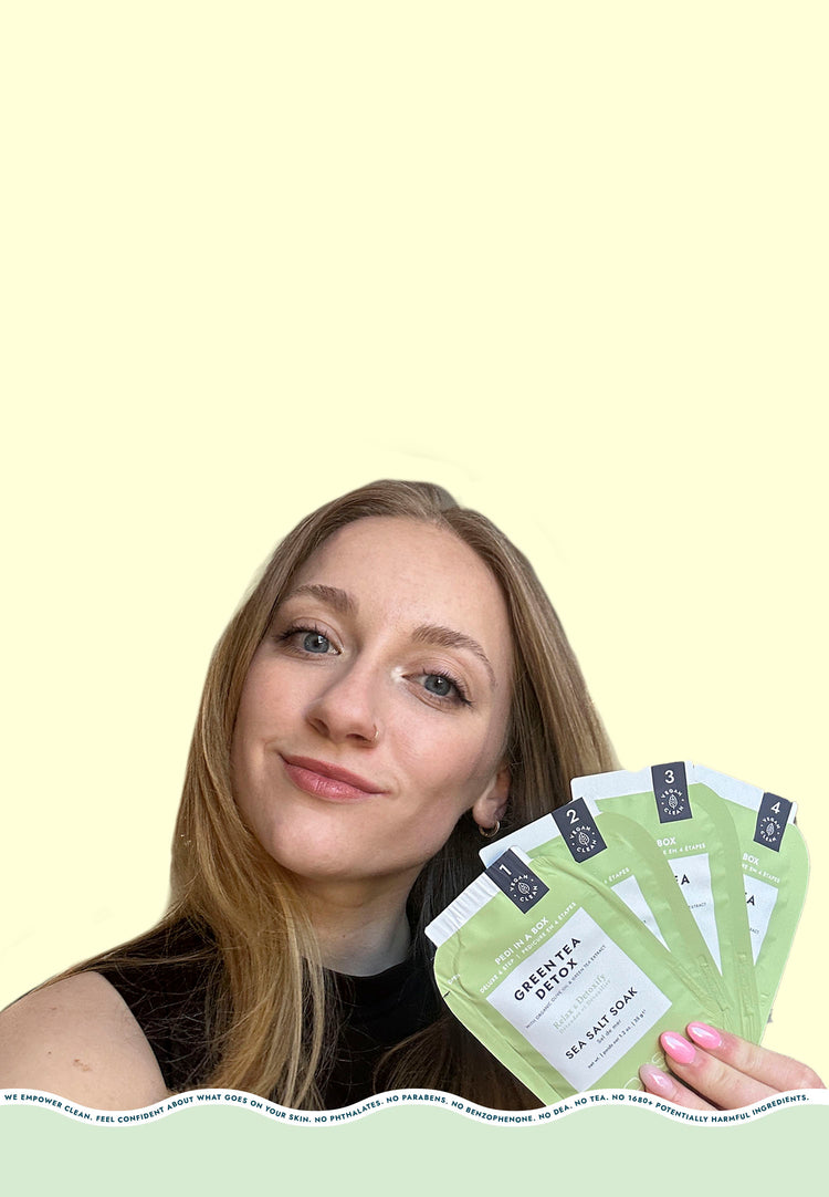 Smiling blonde woman holding 4 sachets from Pedi in a Box Deluxe 4 Step Green Tea Detox on a blue background.