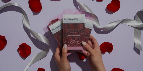 Woman holding Pedi in a box 4 Step Chocolate with both hands and Rose petals surrounded