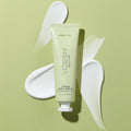 Vegan Body Crème Green Tea pictured on top of the lotion’s texture on a green background.