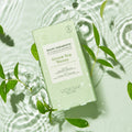 Mani Moments Green Tea Detox on a water background with green leaves.