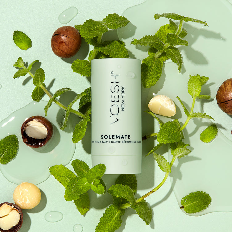 Solemate Heel Repair Balm pictured on a green background with mint leaves and macadamia nuts.