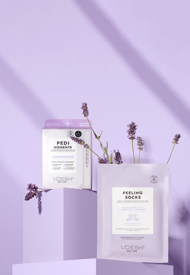 Pedi Moments Lavender Relieve and Peeling Socks on a purple background with sprigs of lavender. 