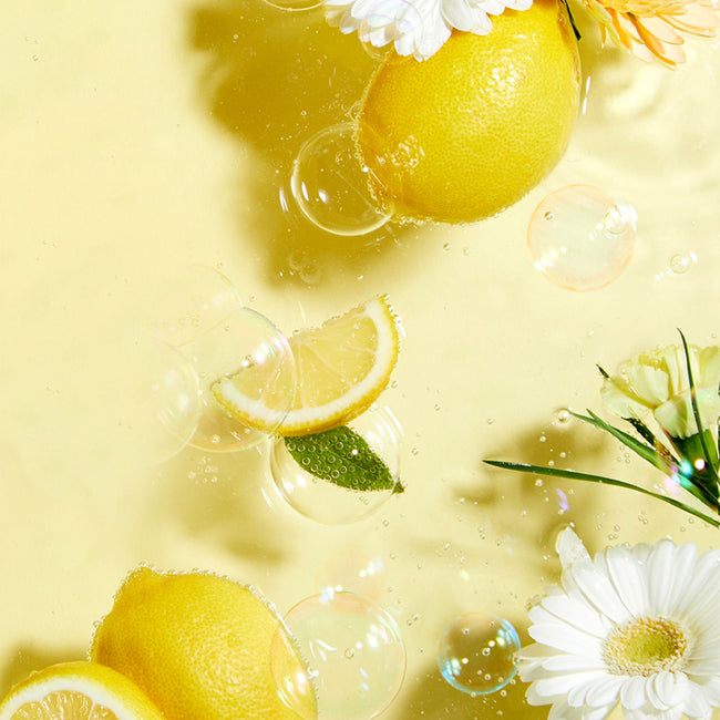 Yellow background with lemons, green leaves, white and yellow flowers floating in water