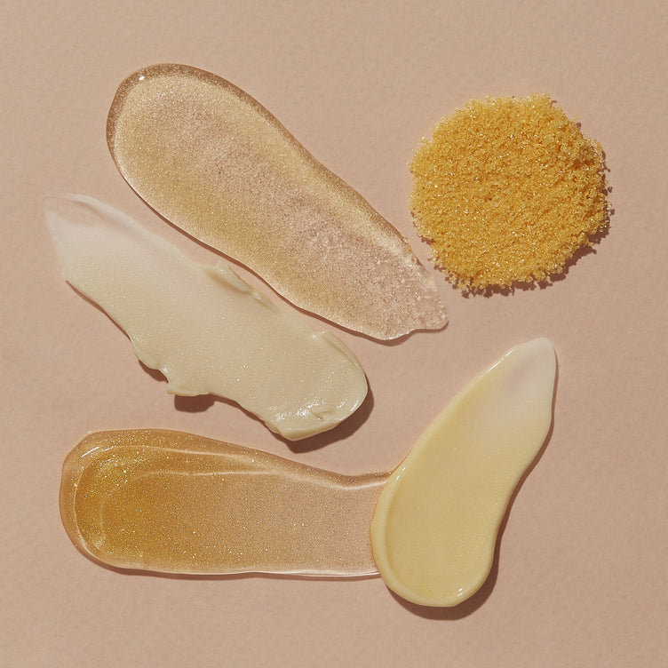 Golden Pedi in a Box Glimmer textures - salt soak, sugar scrub, mud masque, cooling gel, and massage butter on light orange background
