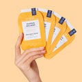 woman's hand holding pedi in a box 4 step mango delight packets on orange background