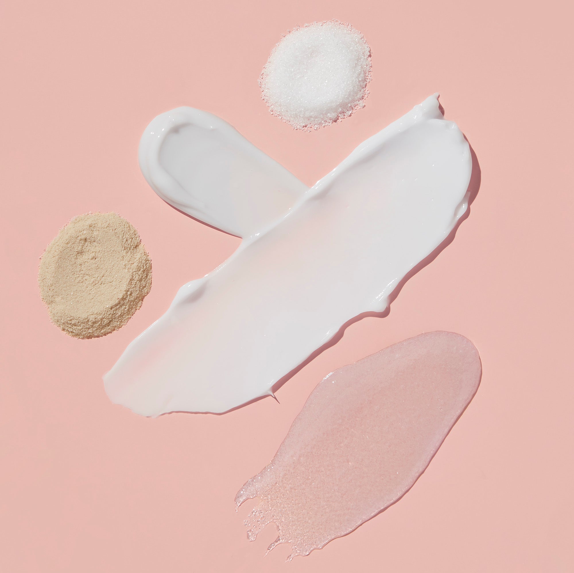 Product texture of Fizz powder, Salt, Scrub Mud masque, Massage butter on light pink background