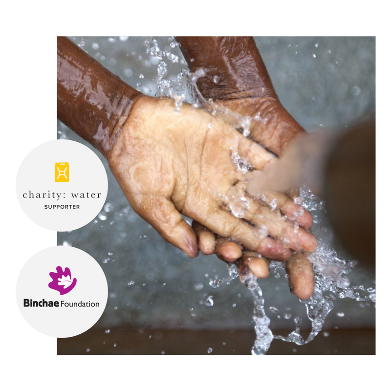 Closeup of hands washing with water with charity water logo and binchae foundation logo in gray circles on the lefthand side