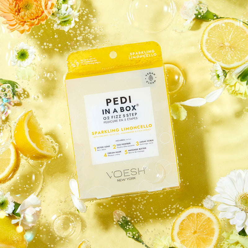 pedi in a box o2 fizz limoncello on yellow background floating in sparkling water with lemon slices, white and yellow flowers
