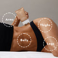 Woman in her bra and underwear lying on her side holding Tone’d Body Firming Roller Crème with a diagram of where to use the product, pictured on a gray background.