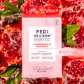 Pomegranate Radiance Pedi in a Box Deluxe 4 Step on background with cut open pomegranates