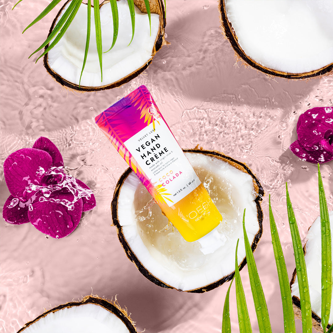 Coco Colada Oasis Vegan Hand & Body Crème on water background with halved coconuts