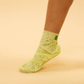Woman's foot wearing Refreshing Odor Treatment Socks on orange background