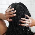Closeup of woman's head from behind scrubbing sugar scrub on hair 