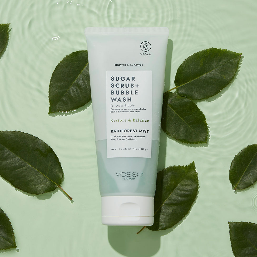 Rainforest Mist Shower & Empower Sugar Scrub in water with green leaves on green background